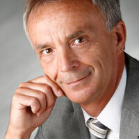 Das Porträt zeigt Klaus Danhamer lächelnd vor grauem Hintergrund.