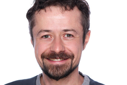 Das Porträt zeigt Simon Richter lächelnd vor weißem Hintergrund.