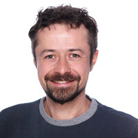Das Porträt zeigt Simon Richter lächelnd vor weißem Hintergrund.